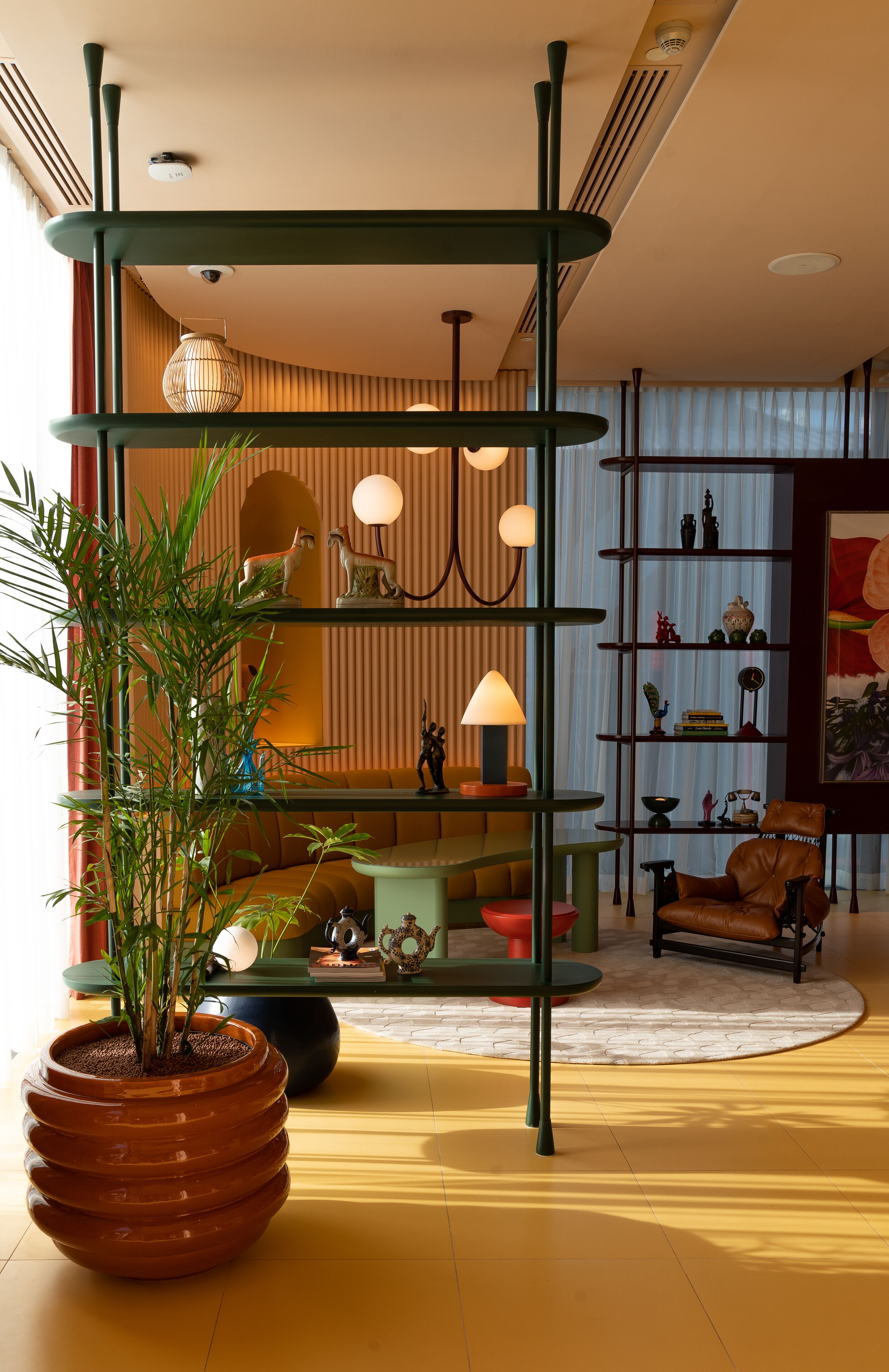 A modern living room with a tiered shelving unit, a potted plant, a sofa, a coffee table, and a chair.