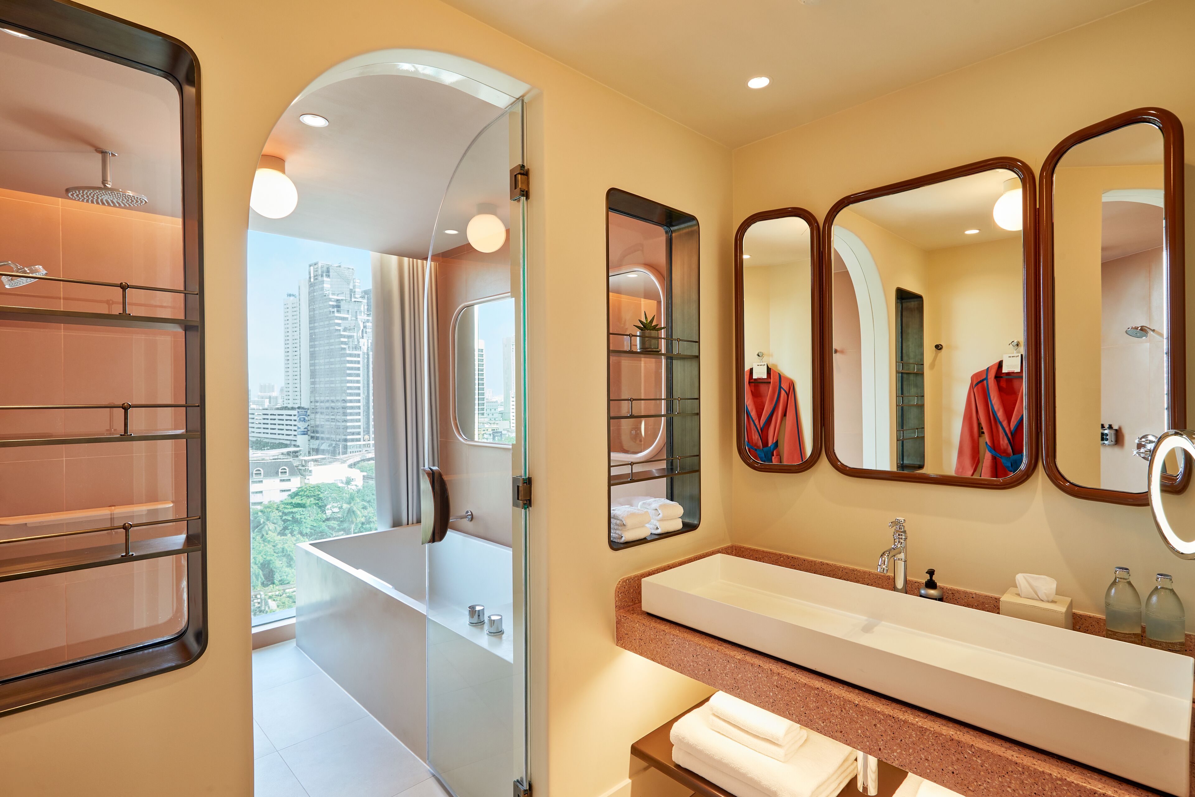 Une salle de bain moderne avec un grand miroir, une baignoire et une vue sur la ville.