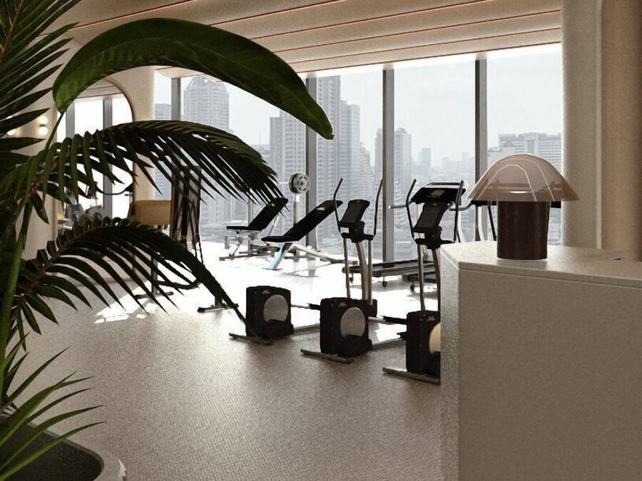 A modern office space with large windows, a standing desk, and exercise equipment.
