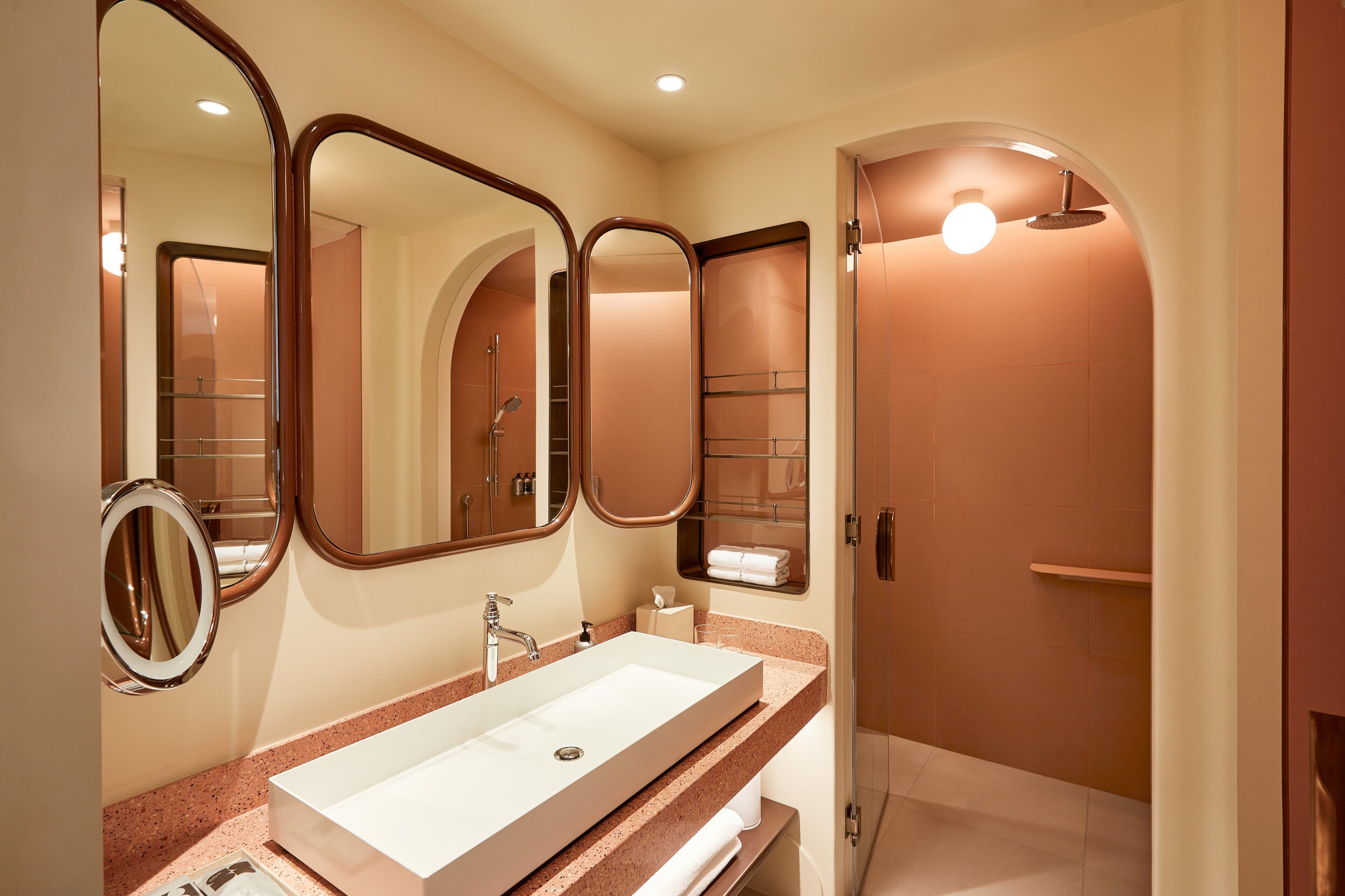 Un baño moderno con un lavamanos grande, espejos y una zona de ducha.