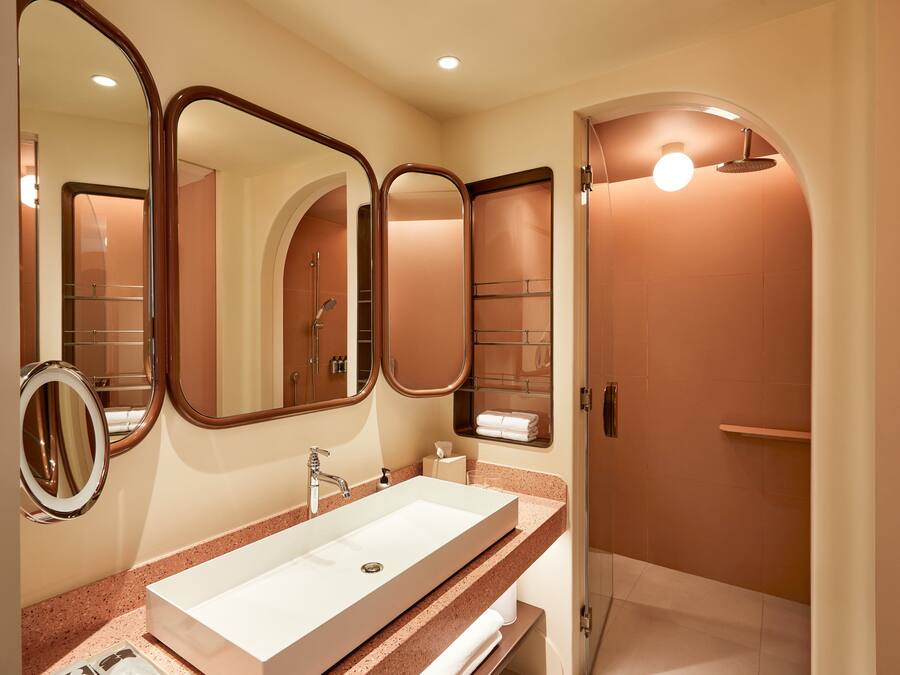 Un baño moderno con un lavamanos grande, espejos y una zona de ducha.