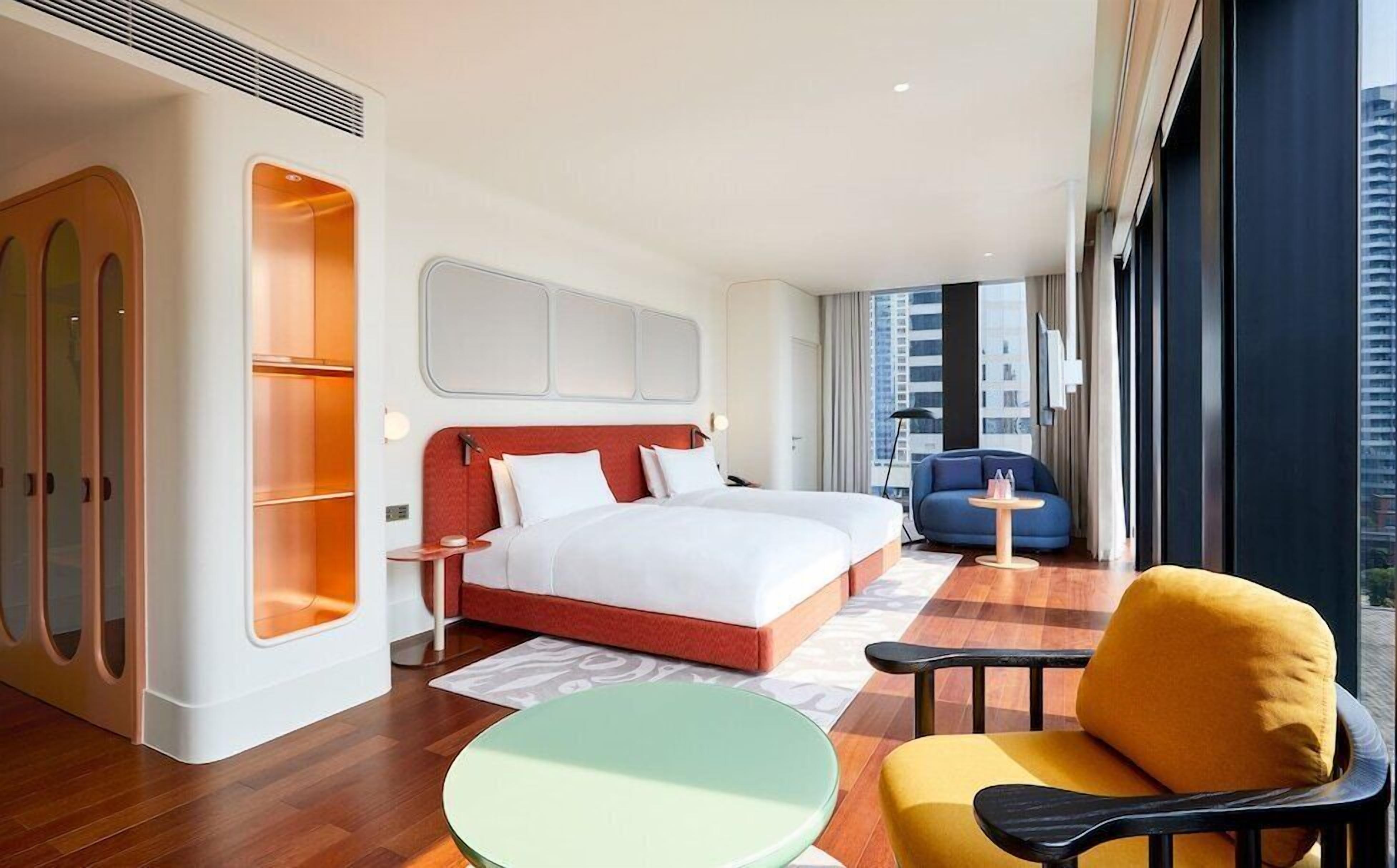 Une chambre d’hôtel avec un lit, une chaise, une petite table et une vue sur la ville.