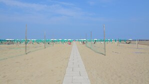 A beach walkway with umbrellas and lounge chairs, leading to the sea. - Resort in Lido di Spina near Adriatic Coast (Lido di Spina)