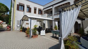 A courtyard with outdoor seating, potted plants, and a covered area. - Resort in Lido di Spina near Adriatic Coast (Lido di Spina)