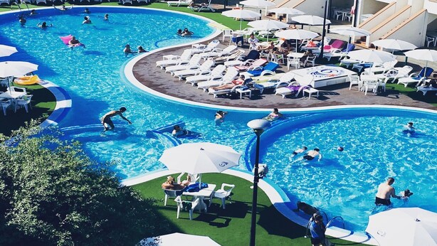 A large outdoor swimming pool with multiple sections, surrounded by lounge chairs and umbrellas. - Resort in Lido di Spina near Adriatic Coast (Lido di Spina)