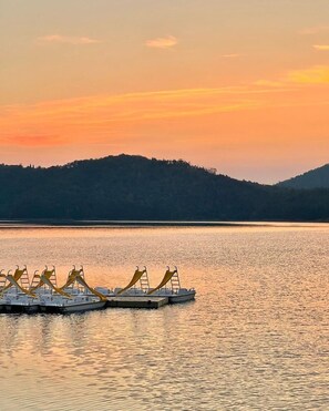 A calm lake at sunset with boats docked in the foreground.