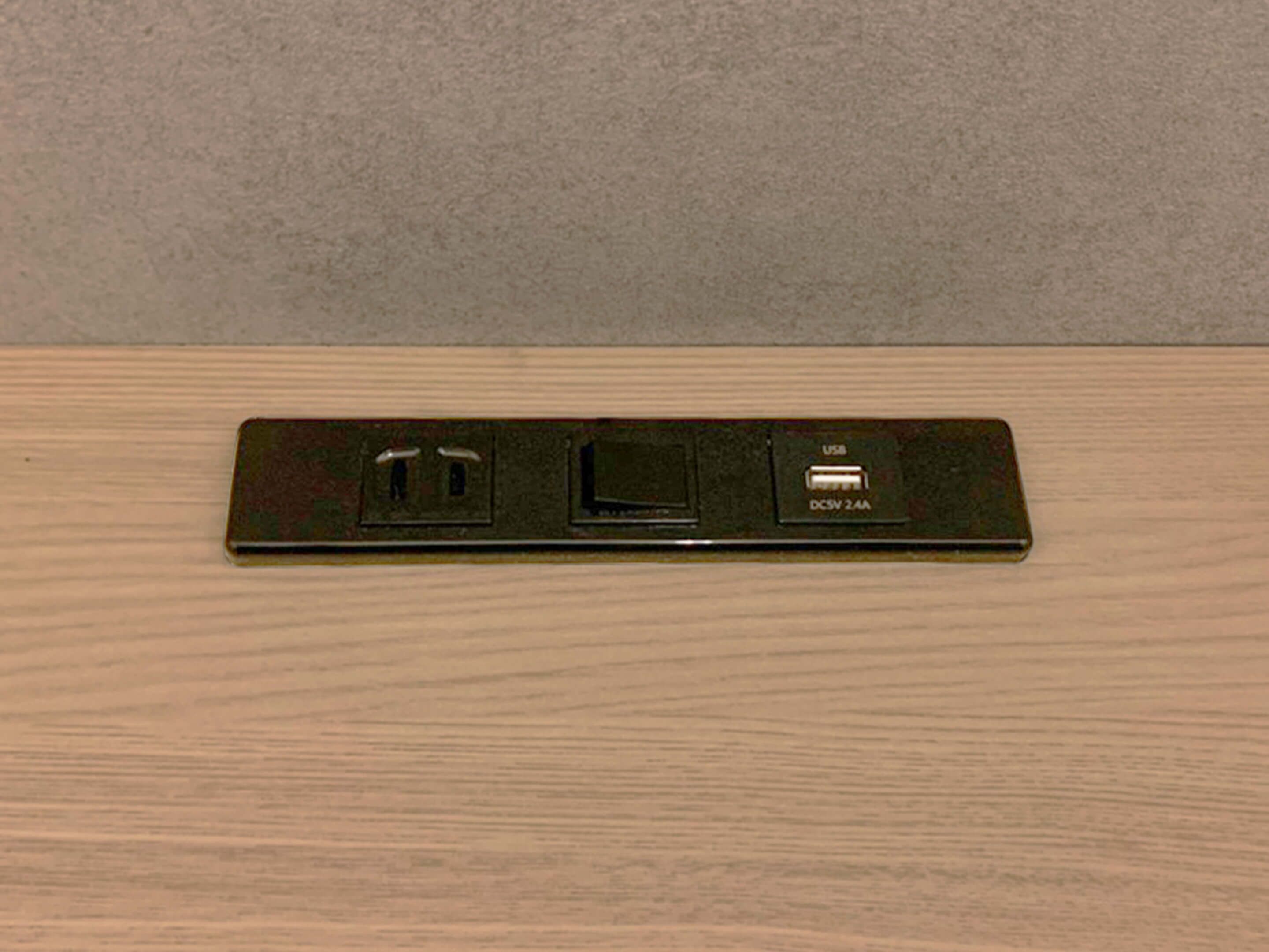 A wall-mounted power strip with two USB ports and a standard electrical outlet.