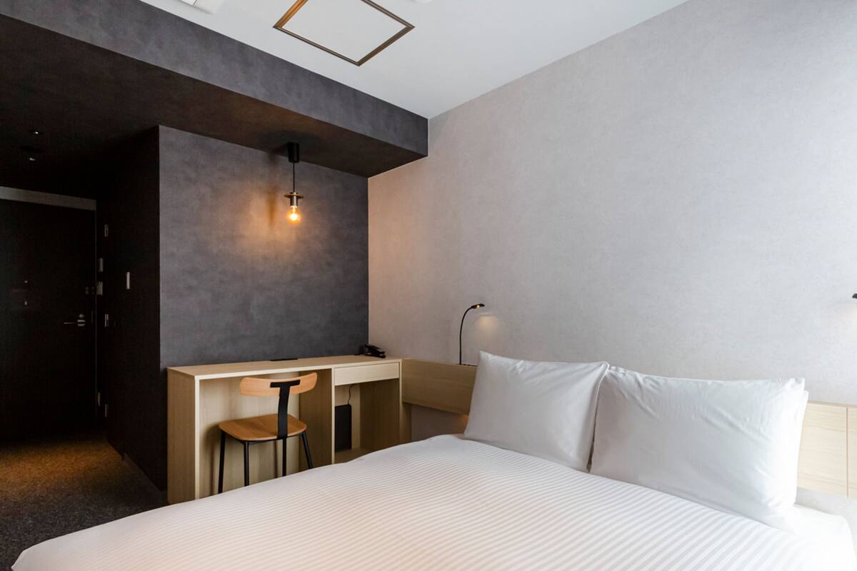 Quarto de hotel moderno com uma cama grande, uma escrivaninha e uma cadeira.