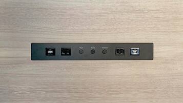 A wall-mounted control panel with USB ports, a display screen, and audio input/output ports.