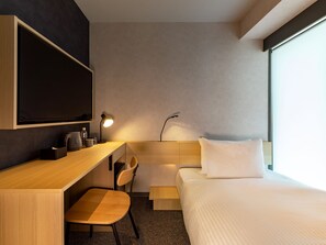 A modern hotel room with a wooden desk, a chair, a bed with white linens, a flat-screen TV mounted on the wall, and a bedside table with a lamp. - AKABANEHOLIC HOTEL (Tokyo)