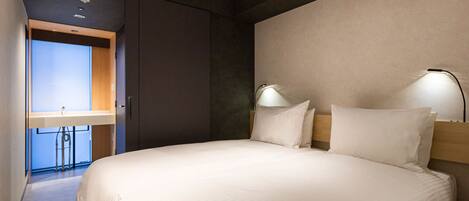 A modern hotel room with a large bed, two bedside lamps, a wooden headboard, and a view of the bathroom.