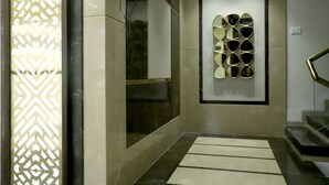 A modern interior with a patterned wall, a decorative mirror wall, and a staircase. - Hotel Grand Girdhar (Indore)