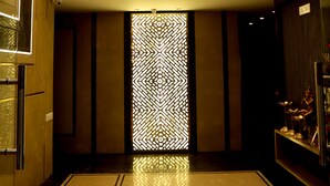 A modern lobby with a high ceiling, a central chandelier, and a patterned wall. - Hotel Grand Girdhar (Indore)