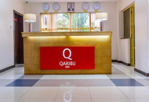 A hotel reception desk with a red sign reading "QARIBU INN". - Qaribu Inn Boutique Hotel Nairobi (Nairobi)