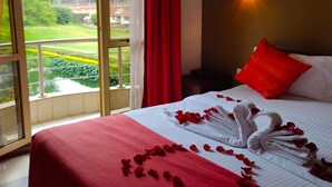 A hotel room with a balcony, a bed with red bedding, a red pillow, and a wall-mounted light. - Qaribu Inn Boutique Hotel Nairobi (Nairobi)