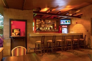 A bar area with wooden chairs and a counter stocked with bottles. - Qaribu Inn Boutique Hotel Nairobi (Nairobi)