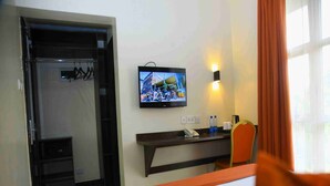 A hotel room with a bed, a desk with a flat-screen TV, a chair, and a window with curtains. - Qaribu Inn Boutique Hotel Nairobi (Nairobi)