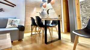 Et moderne interiør med træloft, spisebord med stole, sofa med pude og en stenvæg.