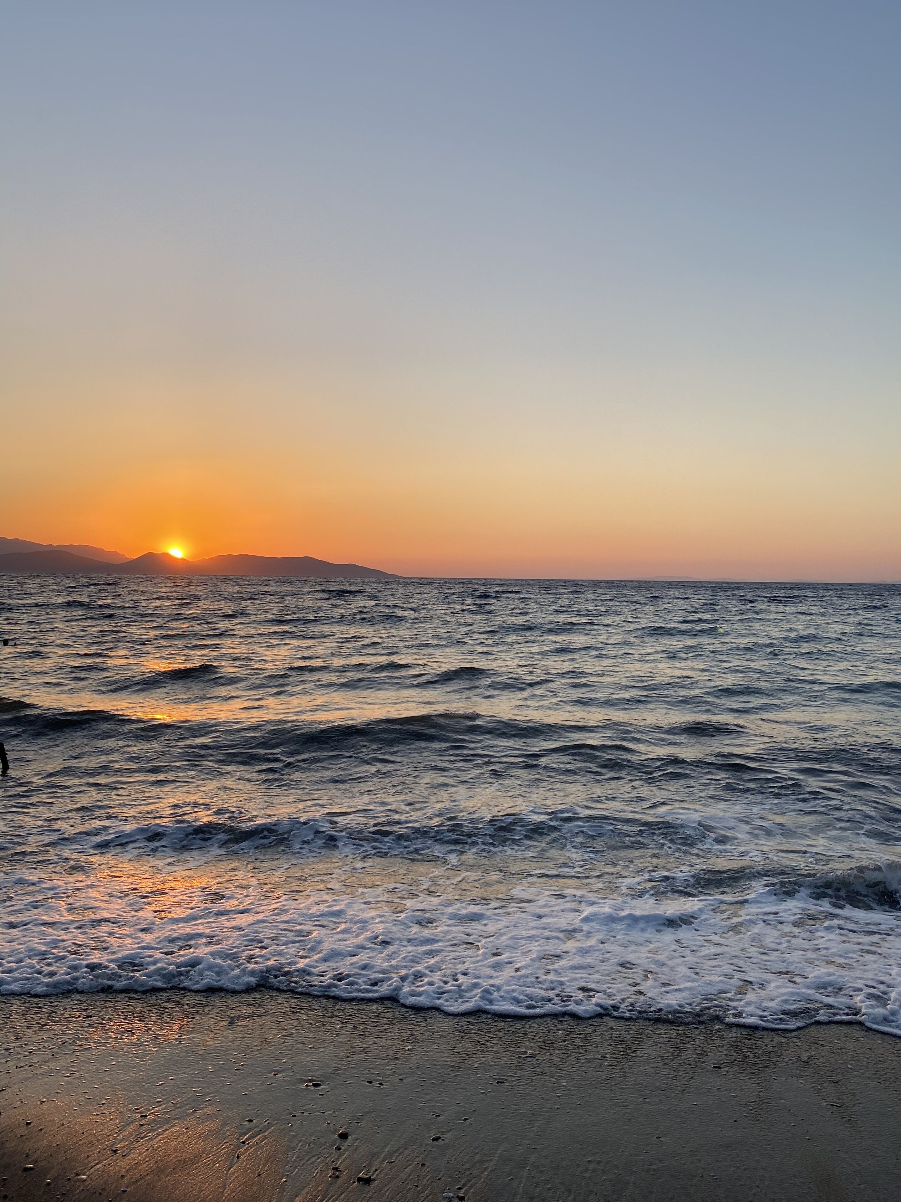 A beach with waves at sunset.