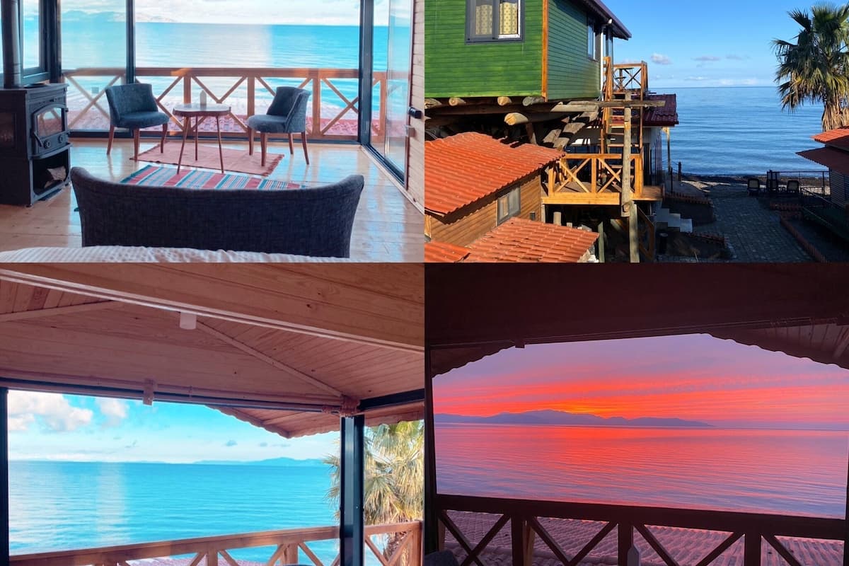 A wooden cabin with a balcony overlooking the sea, furnished with chairs and a table.