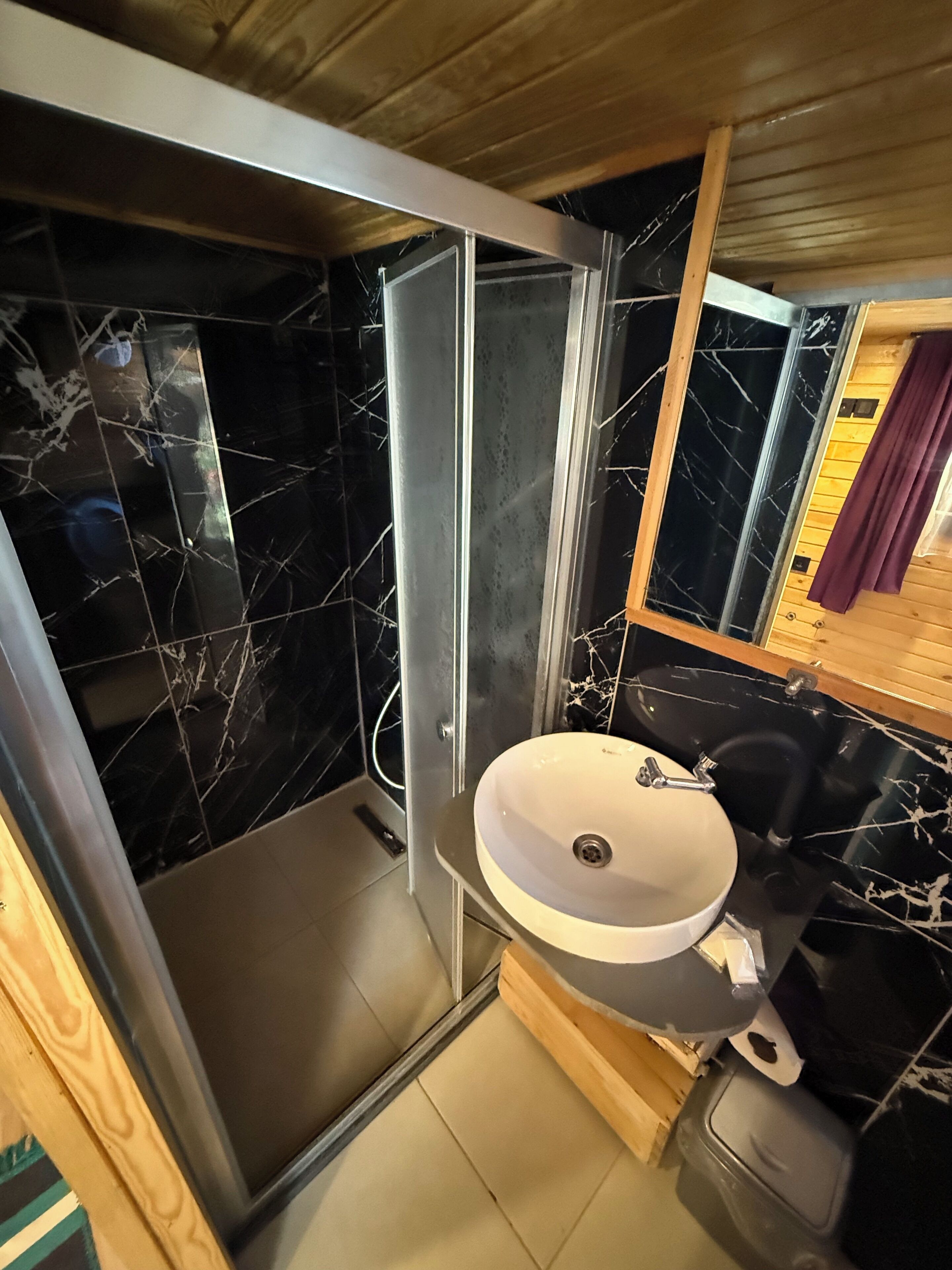 Un baño pequeño con ducha de vidrio, lavamanos y espejo.