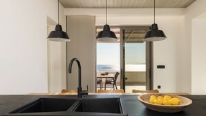 Una cocina moderna con encimera negra, lavamanos doble y luces colgantes.