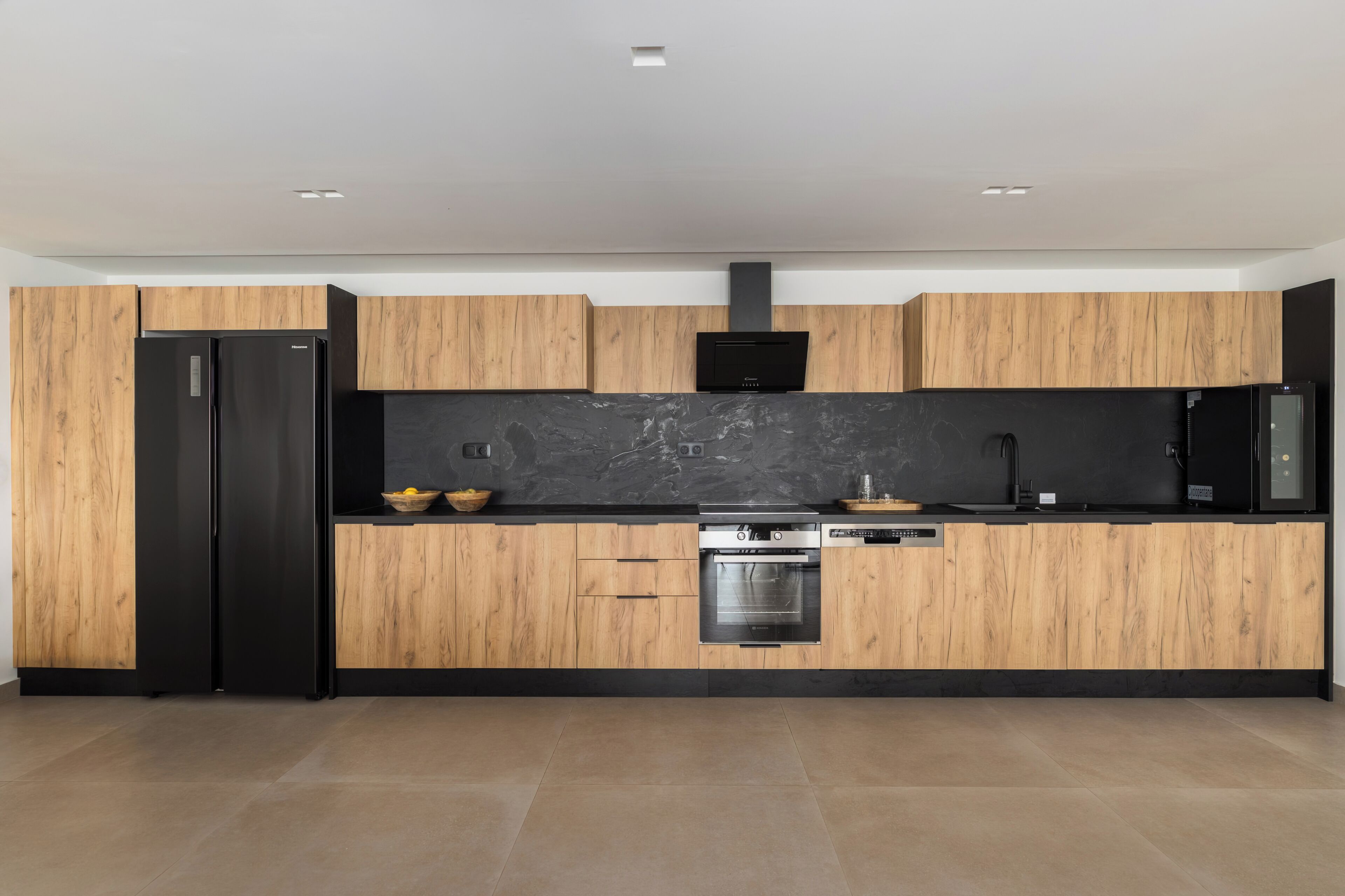 Una cocina moderna con armarios de madera, encimera negra y electrodomésticos de acero inoxidable.