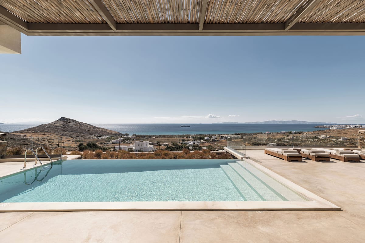 Una piscina infinita en la azotea con vistas a un paisaje montañoso y al mar.