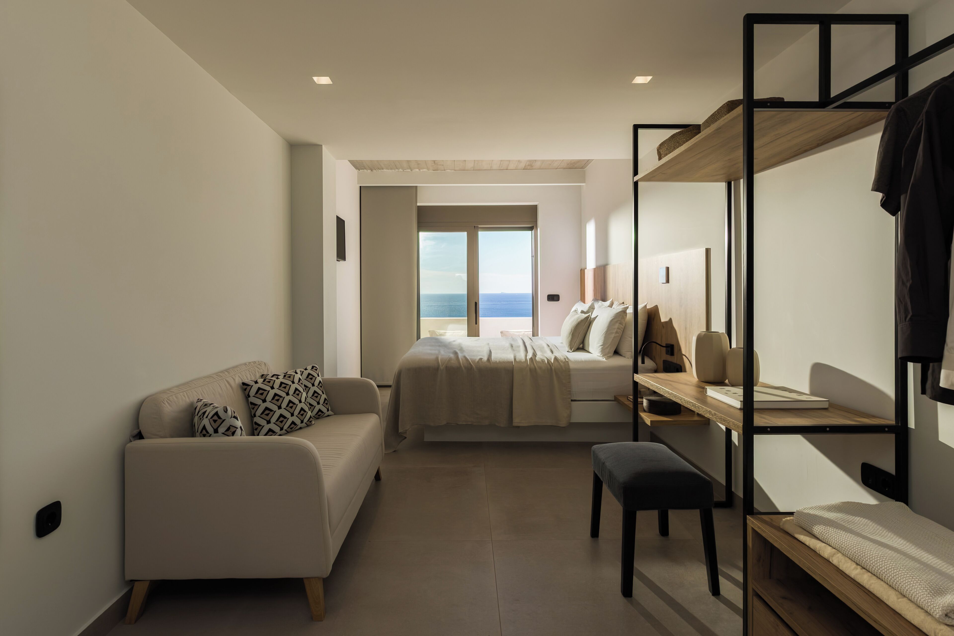 Una habitación pequeña con cama, sofá, escritorio y literas.