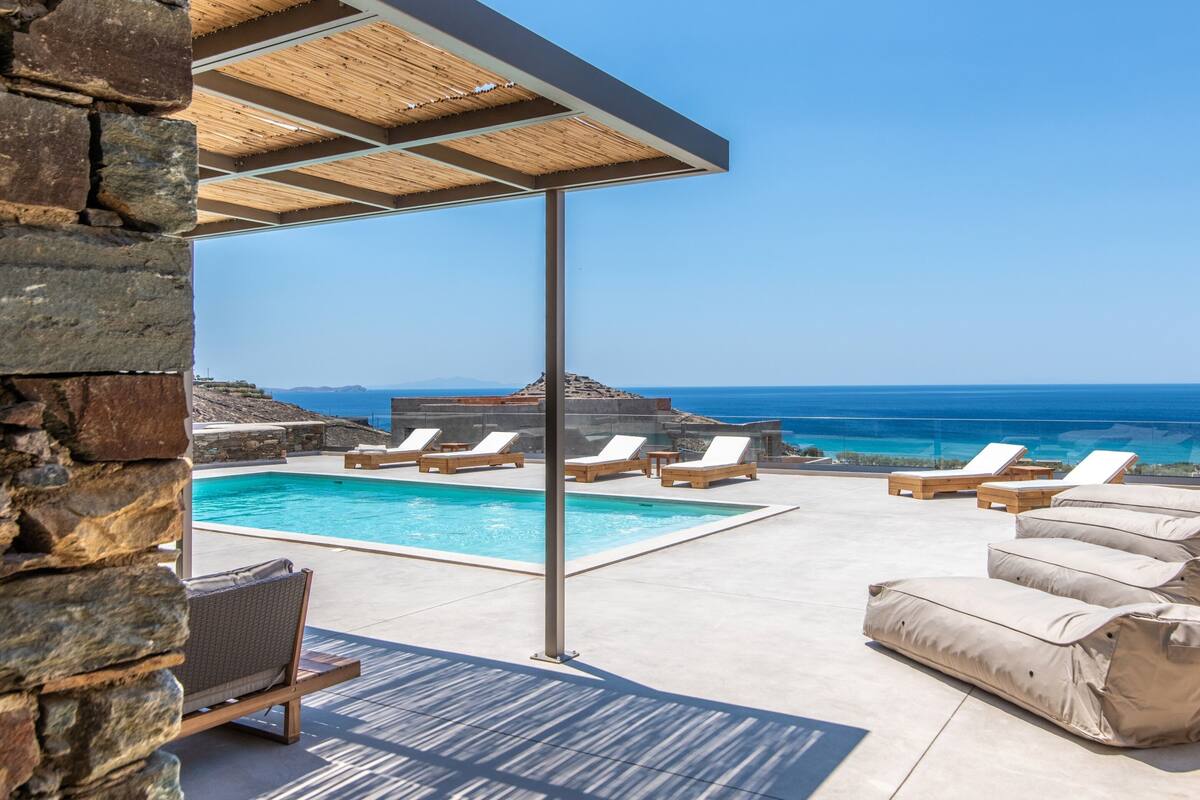 Zona de piscina con sillas de descanso y vista al océano.