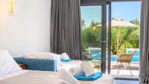 A hotel room with a bed, a blue sofa, a pool view, and a chair by the pool. - Alonaki Resort (Preveza)