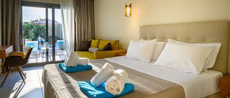 A hotel room with a large bed, a sofa, a desk, and a balcony with outdoor furniture.