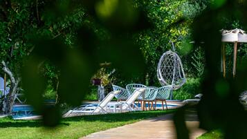 Un espace jardin aménagé avec une piscine, des chaises longues et une pergola.