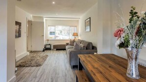 A modern living room with a sofa, a wooden coffee table, and a vase with flowers.