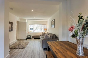 Un salon moderne avec un canapé, une table basse en bois et un vase rempli de fleurs.