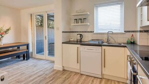 A modern kitchen with a dishwasher, a sink, and a window with blinds.
