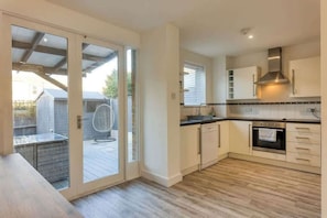 Une cuisine moderne avec une porte-fenĂȘtre coulissante donnant sur un patio extĂ©rieur.