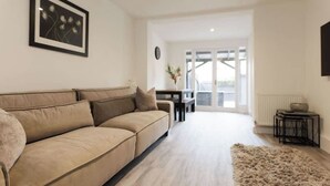 A modern living room with a beige sofa, a fluffy rug, and a framed picture on the wall.