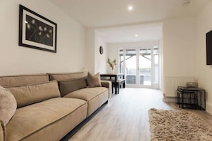 Un salon moderne avec un canapé beige, un tapis moelleux et un tableau encadré accroché au mur.