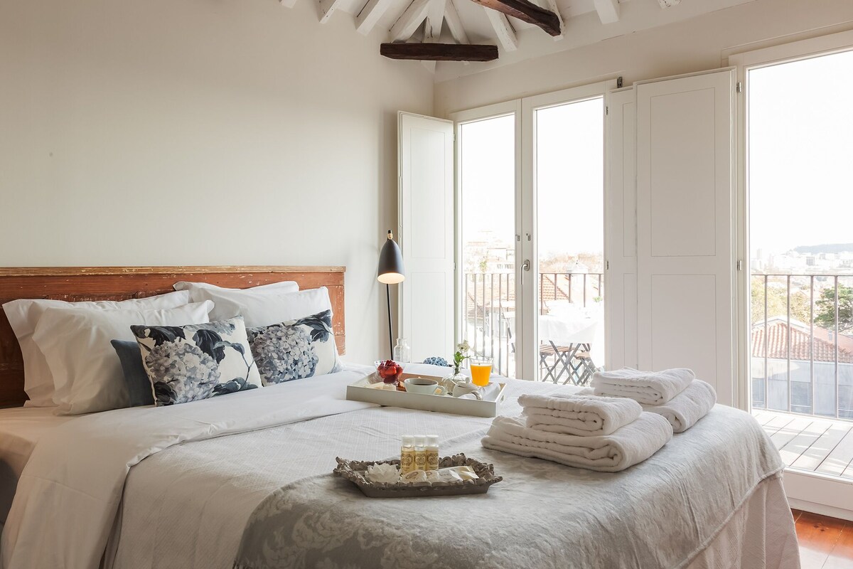 A bedroom with a bed, pillows, a tray with toiletries, and a balcony view.