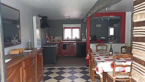 A kitchen with a gas stove, sink, and red cabinets. There is a dining table with chairs and a red and white checkered tablecloth. - Vacation home for 10 people 1h15 from Paris (Venon)
