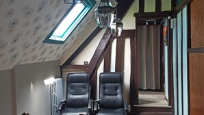 A room with a sloped ceiling, two black leather chairs, a wooden staircase, and a radiator. - Vacation home for 10 people 1h15 from Paris (Venon)