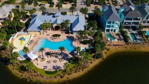 Vista aérea de um resort com uma piscina grande, vários edifícios e palmeiras.