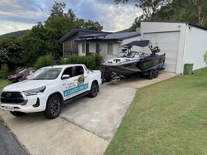 Una camioneta pickup blanca con un remolque para barcos estacionada frente a una casa.