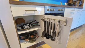 Cozinha com armários brancos, fogão e utensílios pendurados em um suporte.