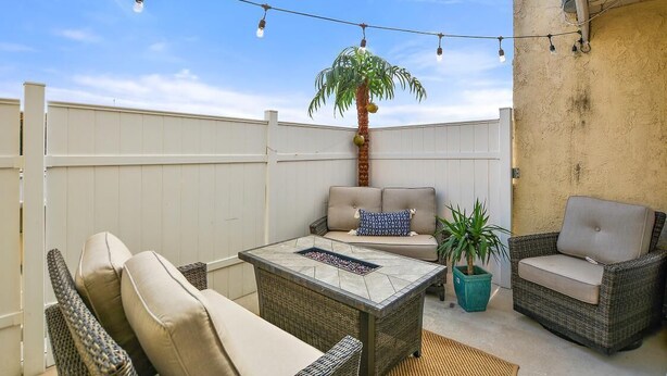 Eine Terrasse im Freien mit Korbmöbeln, einer Palme und Lichterketten.