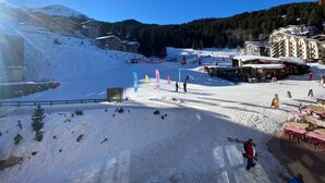 Estância de esqui com encosta coberta de neve, teleféricos e edifícios ao fundo.