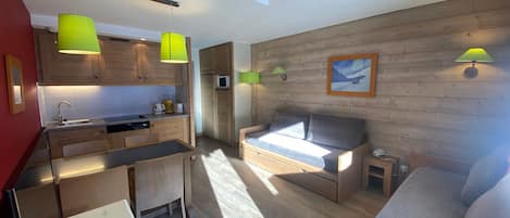 A compact living space with a kitchenette, a sofa, and a dining area.