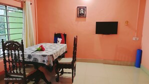 Ein Essbereich mit Tisch, Stühlen, einem Fernseher und einem gerahmten Bild an der Wand.