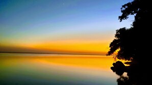 Ruhige Wasserfläche spiegelt einen Sonnenuntergangshimmel.
